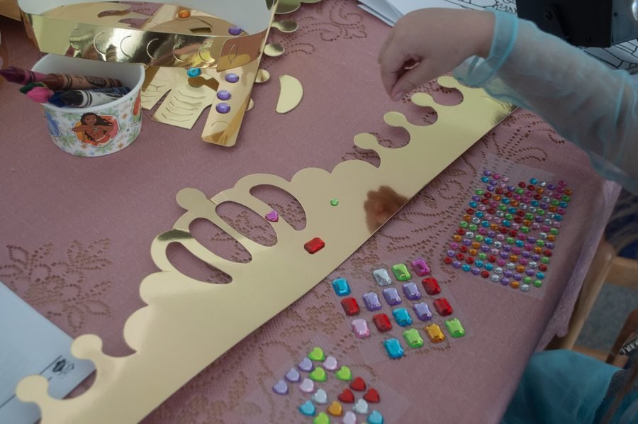 Child decorating a crown with jewels at a themed birthday party