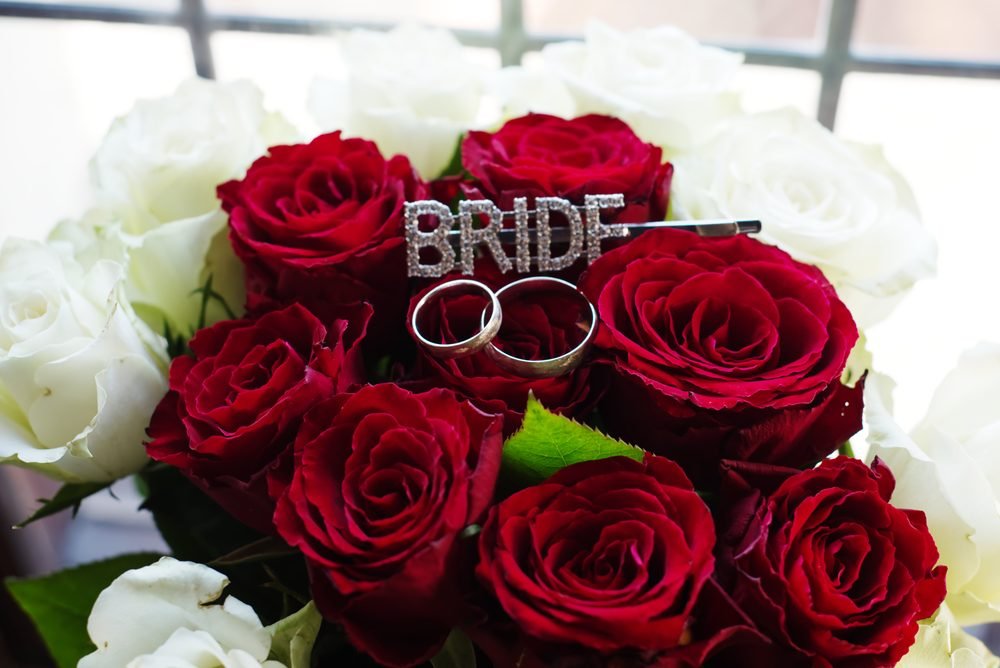 Wedding rings nestled in a red rose bouquet