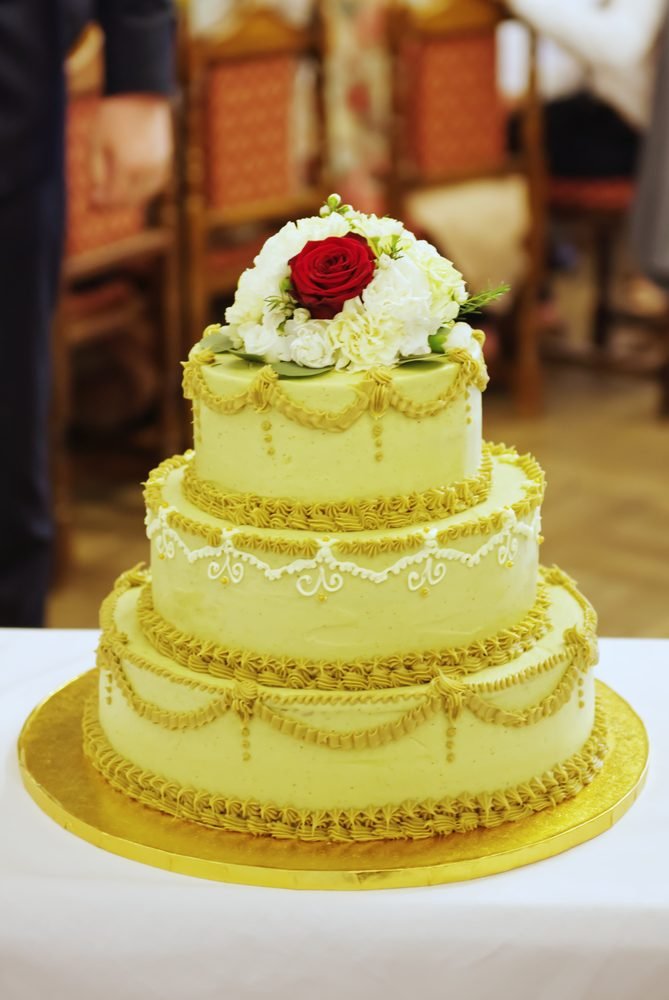 Three-tier wedding cake topped with a red rose and white flowers